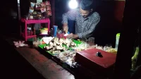 Penjual angkringan menyiapkan sate dan gorengan di warung malam hari