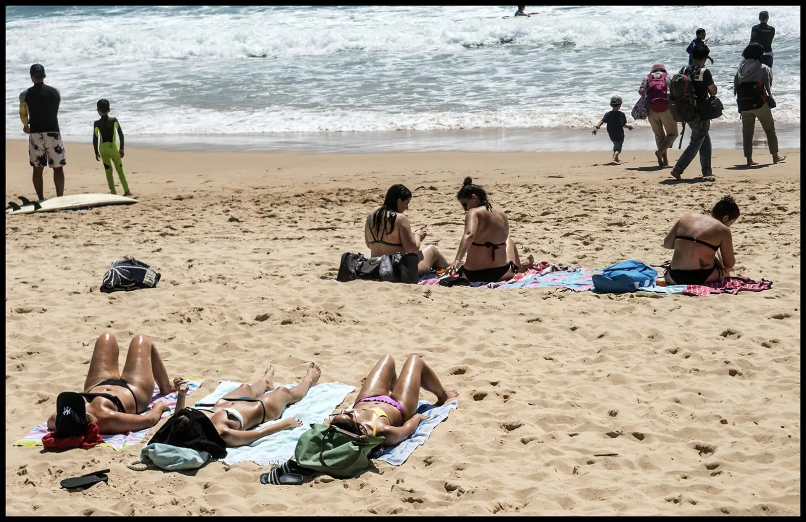 Pengunjung berjemur di pantai berpasir saat siang terik, kondisi yang menuntut sunscreen untuk kulit berjerawat