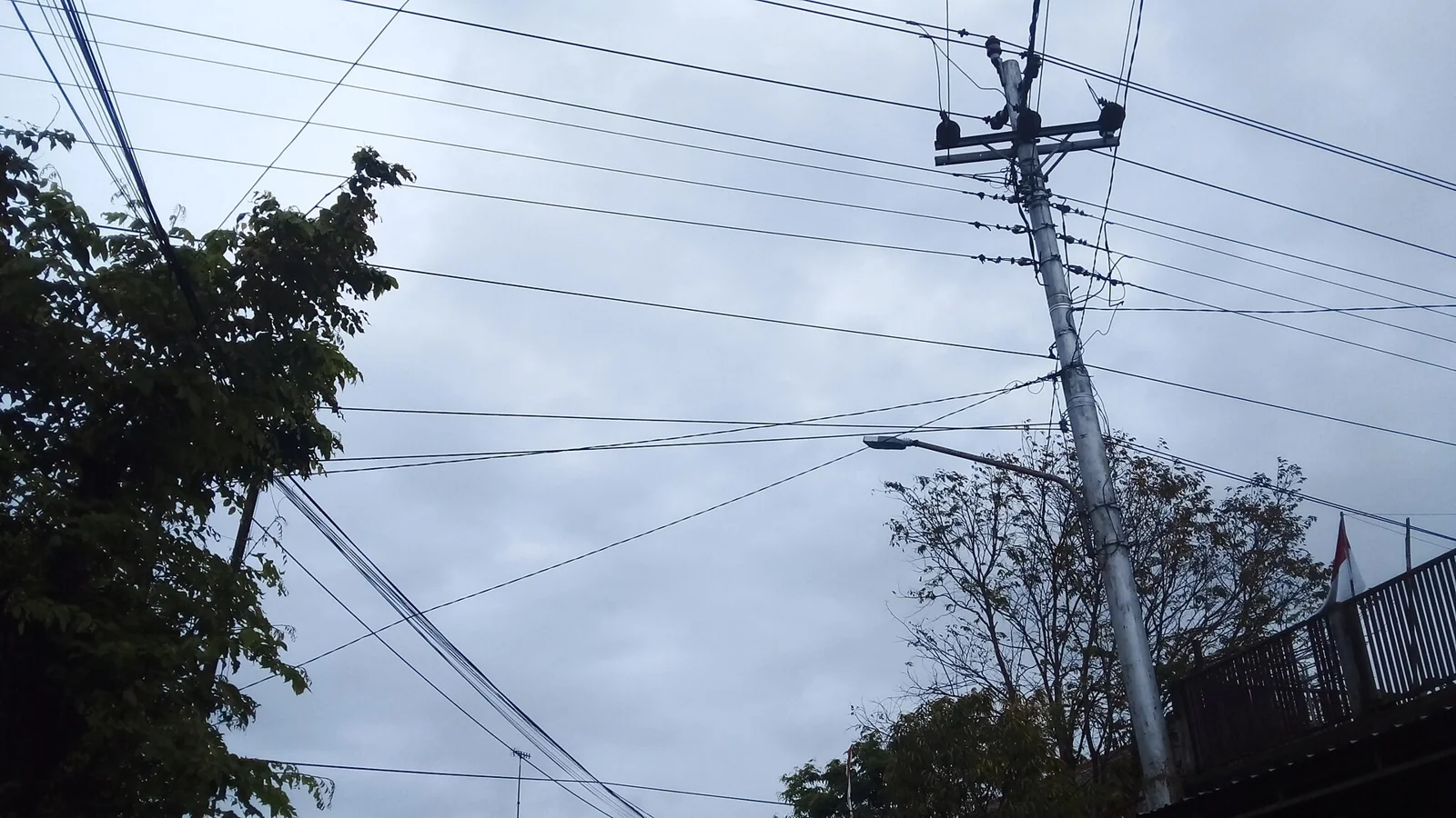 Tiang listrik PLN dengan banyak kabel jaringan di bawah langit mendung, tarif listrik Oktober 2026 masih menunggu keputusan