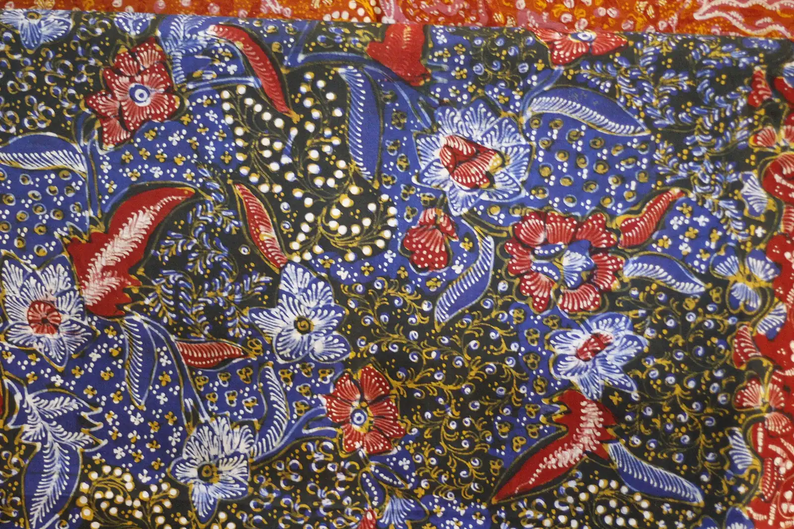 Kain batik motif kreasi Tiga Negeri berwarna biru dan merah dengan motif bunga dan burung