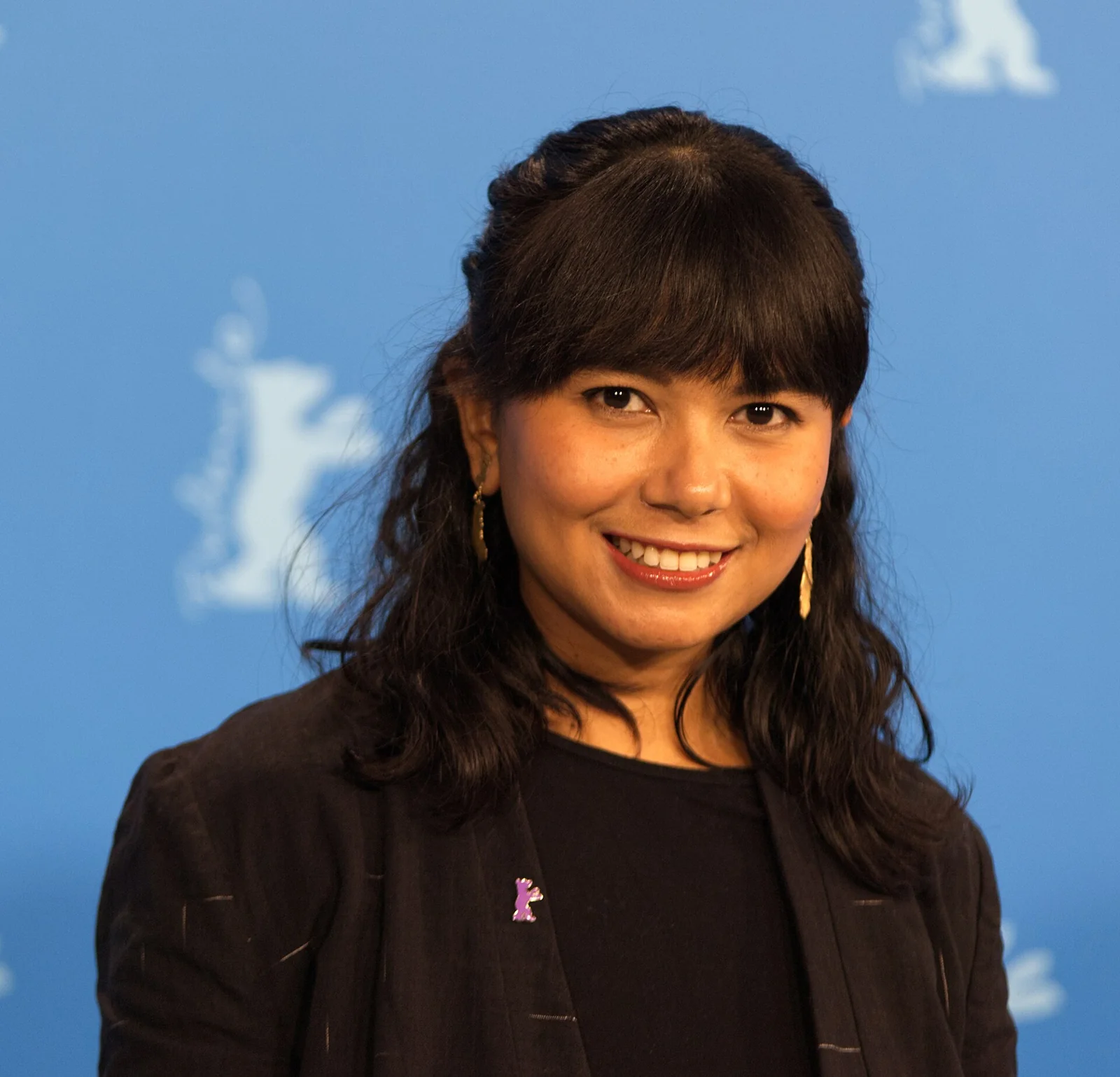 Sutradara Kamila Andini tersenyum di depan latar Berlinale 2022