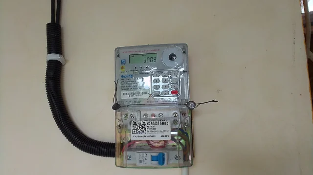 Meteran listrik prabayar digital PLN terpasang di dinding rumah