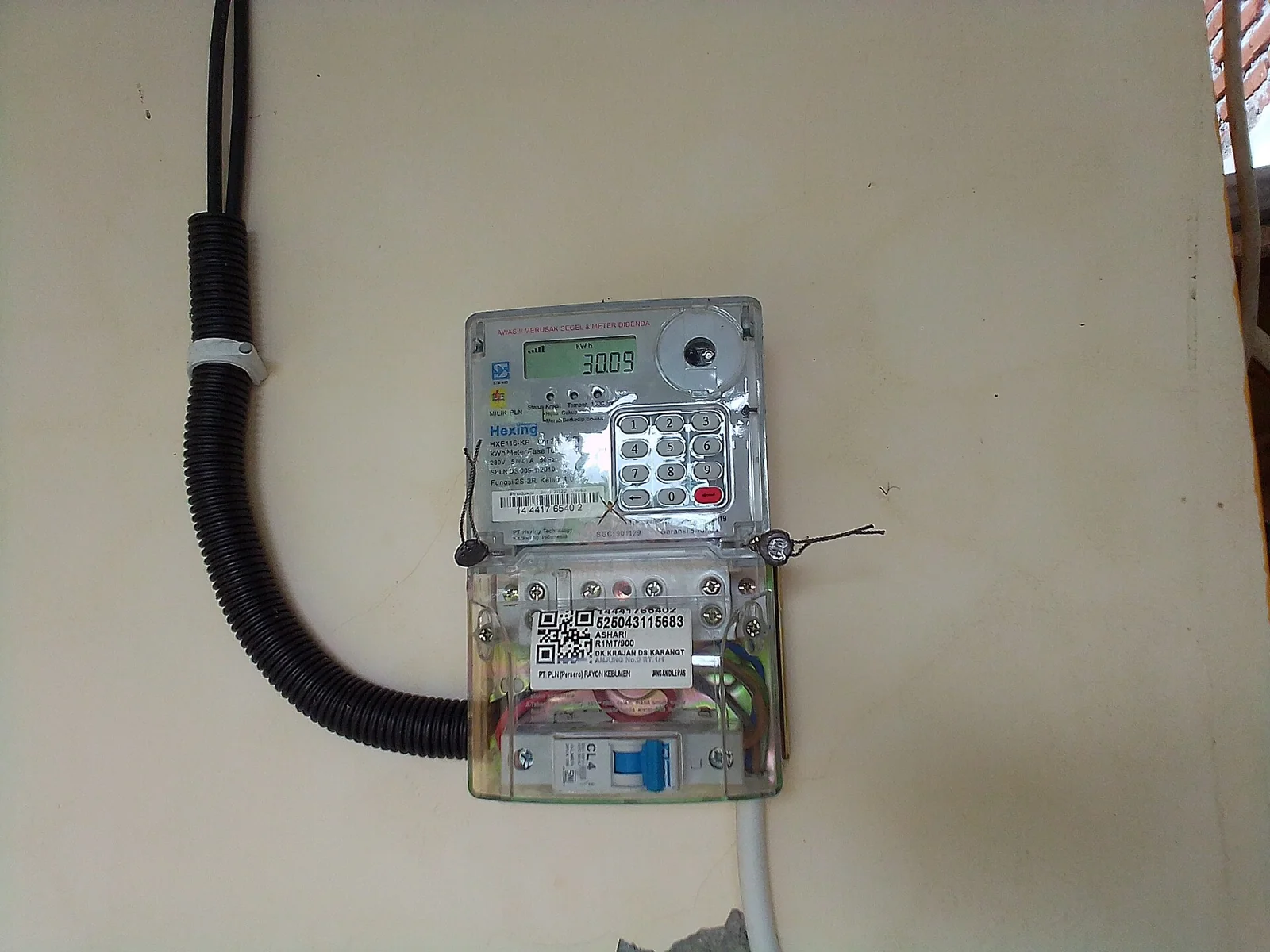 Meteran listrik prabayar digital PLN terpasang di dinding rumah
