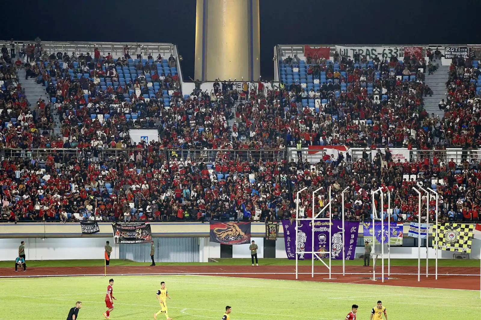 Pertandingan malam Timnas Indonesia berbaju merah dengan tribun penuh suporter