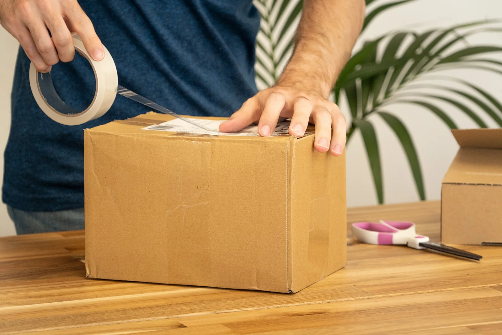 Tangan menempelkan label pengiriman pada kardus paket dengan lakban