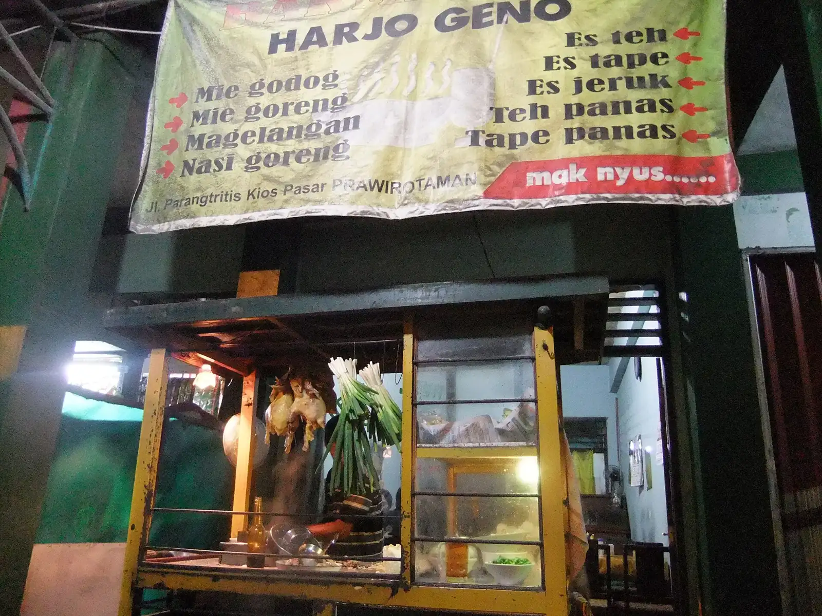 Warung bakmi Jawa dengan spanduk daftar menu di pasar malam, contoh UMKM yang mengurus legalitas dan pajak usaha