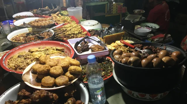 Warung makan malam di Yogyakarta dengan aneka lauk tertata di atas nampan dan baskom