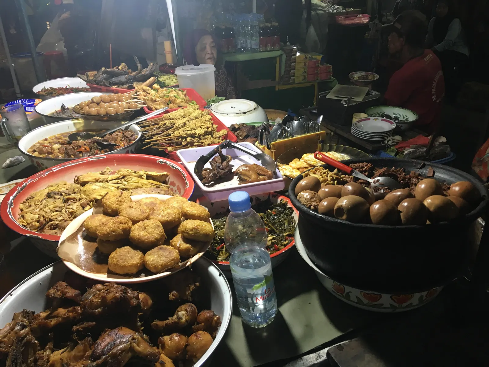 Warung makan malam di Yogyakarta dengan aneka lauk tertata di atas nampan dan baskom