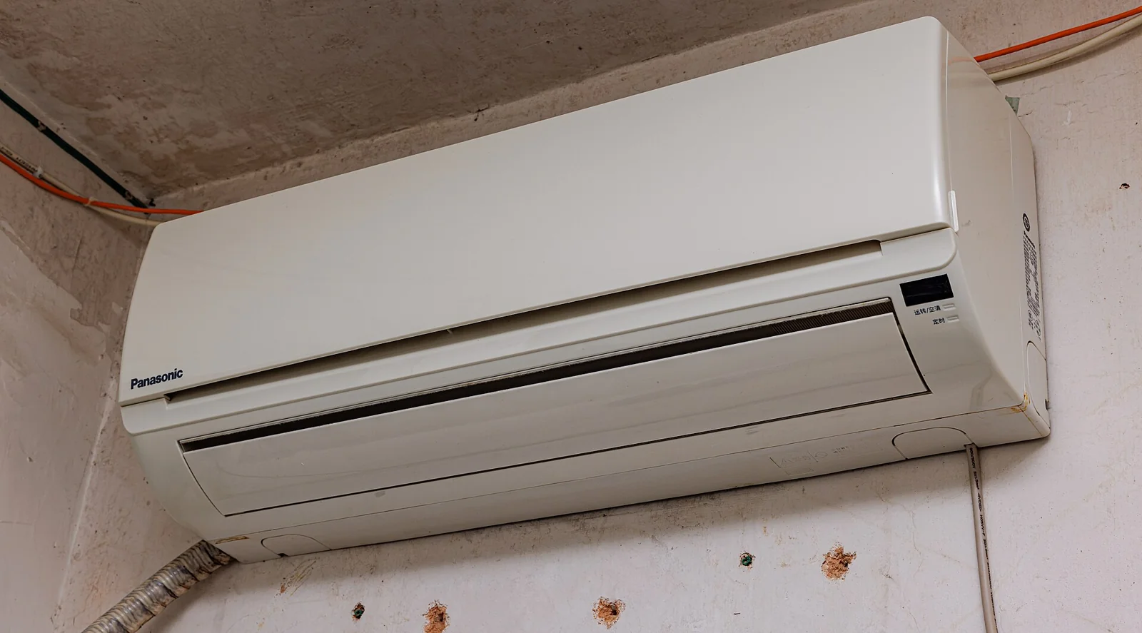 Unit indoor AC split putih terpasang di dinding dekat langit-langit