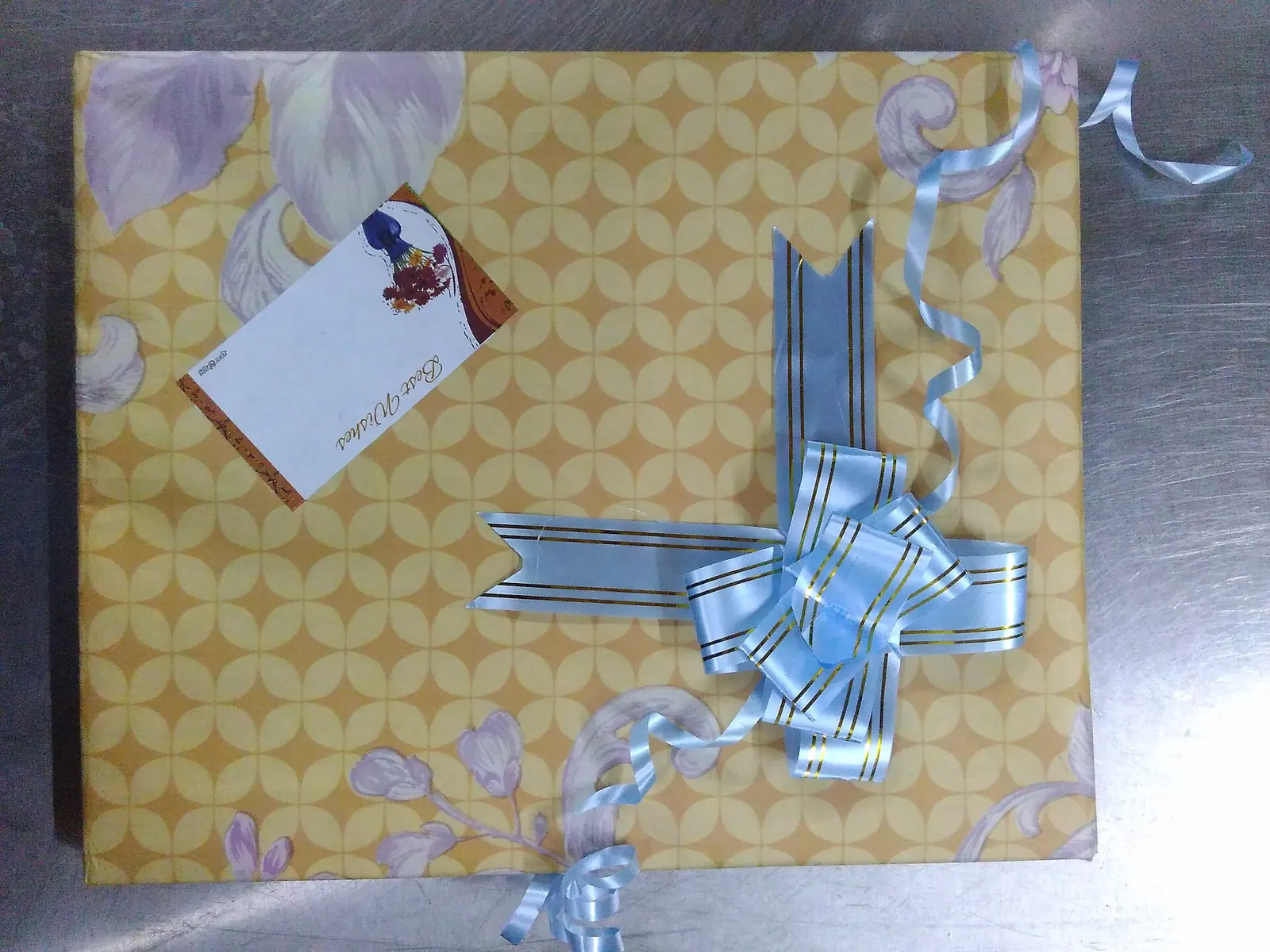 Kotak hadiah berpita biru dengan kertas bermotif kuning
