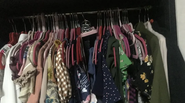Deretan baju bermotif tergantung rapat di dalam lemari pakaian