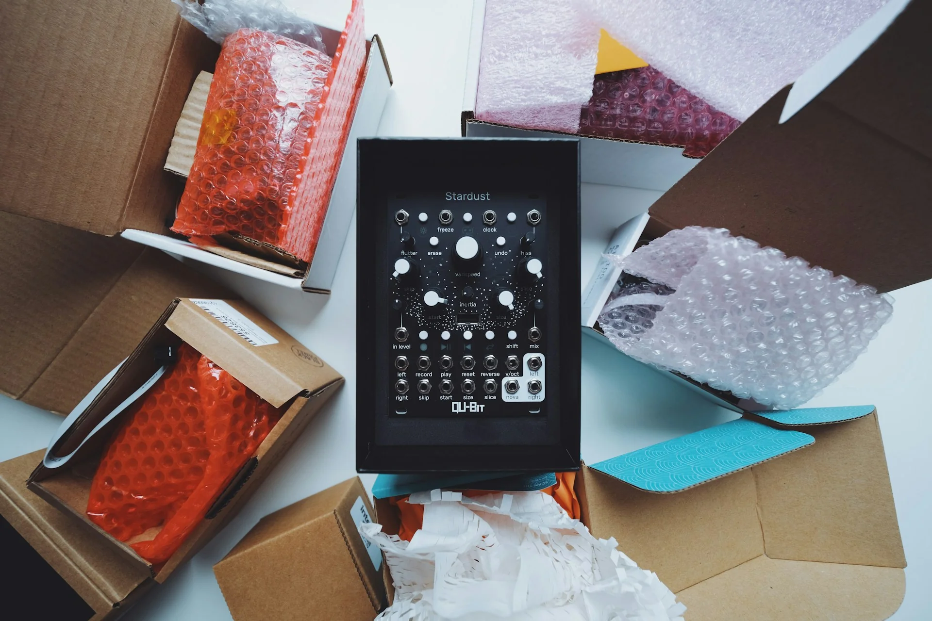 Perangkat elektronik di tengah kardus terbuka berisi bubble wrap dan kertas pelindung