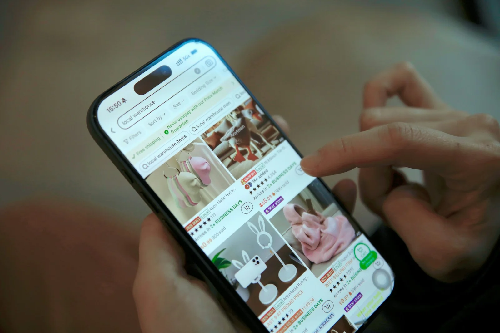 Tangan menggulir daftar produk di aplikasi marketplace pada layar ponsel