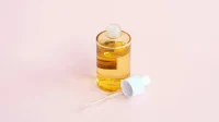 Botol serum kaca berisi cairan kuning dengan pipet di samping, ilustrasi retinol untuk pemula