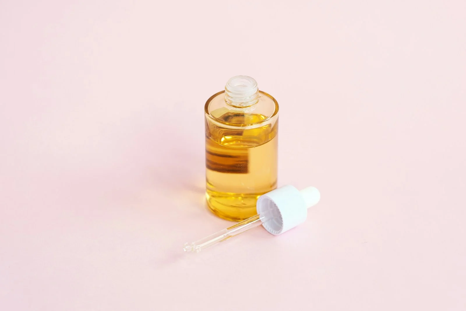 Botol serum kaca berisi cairan kuning dengan pipet di samping, ilustrasi retinol untuk pemula