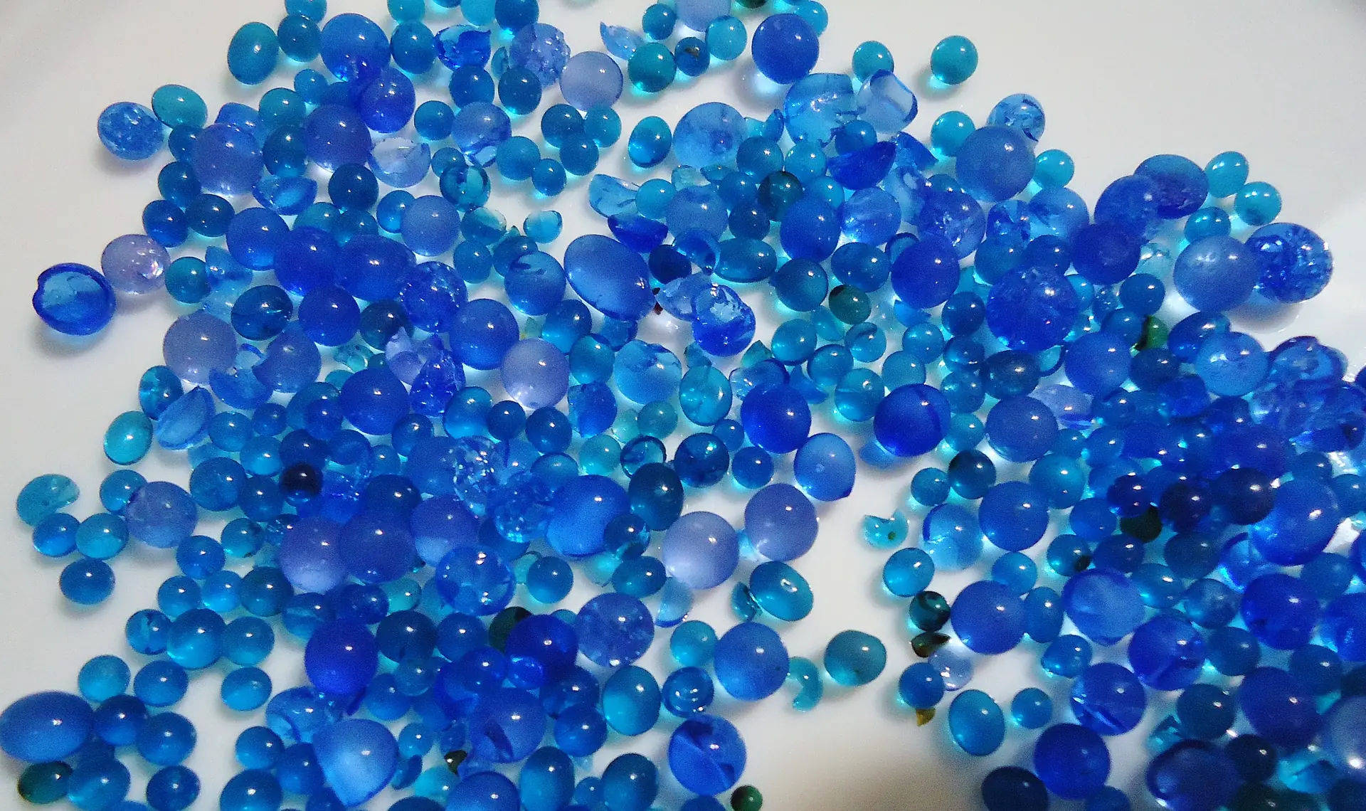Butiran silika gel berwarna biru berserakan di atas permukaan putih