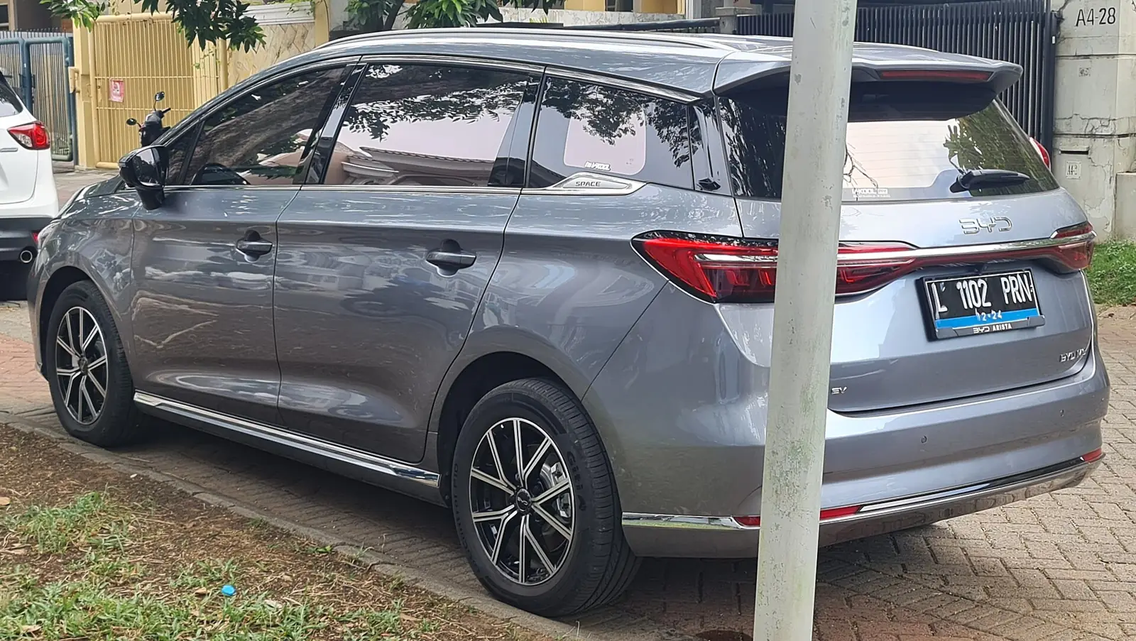 BYD M6 warna abu-abu berpelat Surabaya terparkir dilihat dari belakang kanan