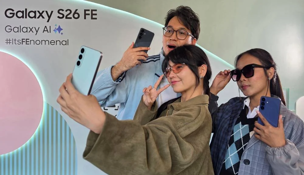 Tiga anak muda berswafoto memakai Galaxy S26 FE di peluncuran Indonesia