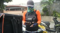 gudang-paket Truk pengiriman marketplace berwarna oranye dan kurir bermotor di depan ruko