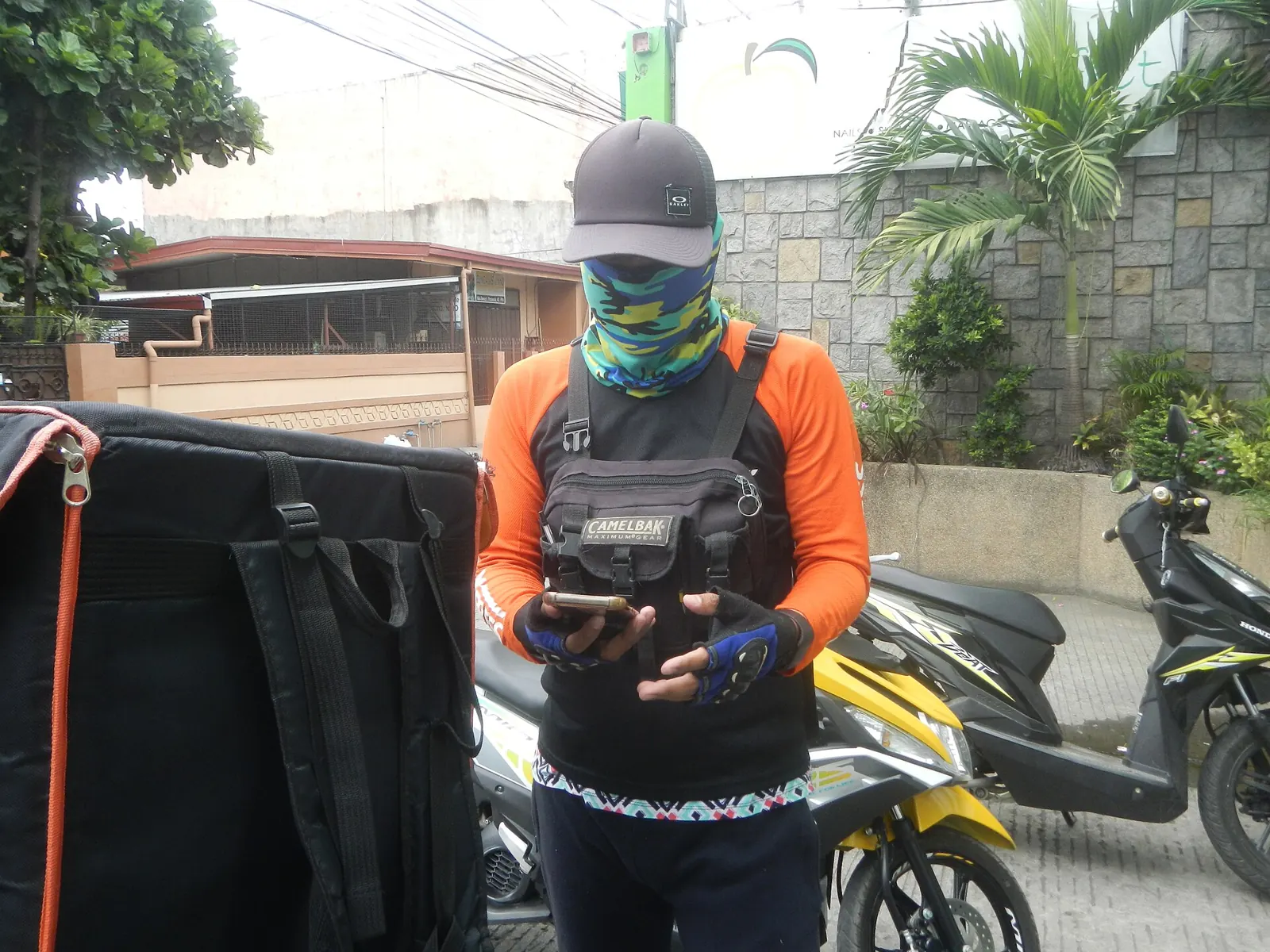 Truk pengiriman marketplace berwarna oranye dan kurir bermotor di depan ruko
