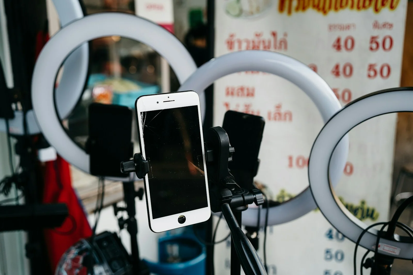 Ponsel terpasang di dudukan tripod di depan beberapa ring light