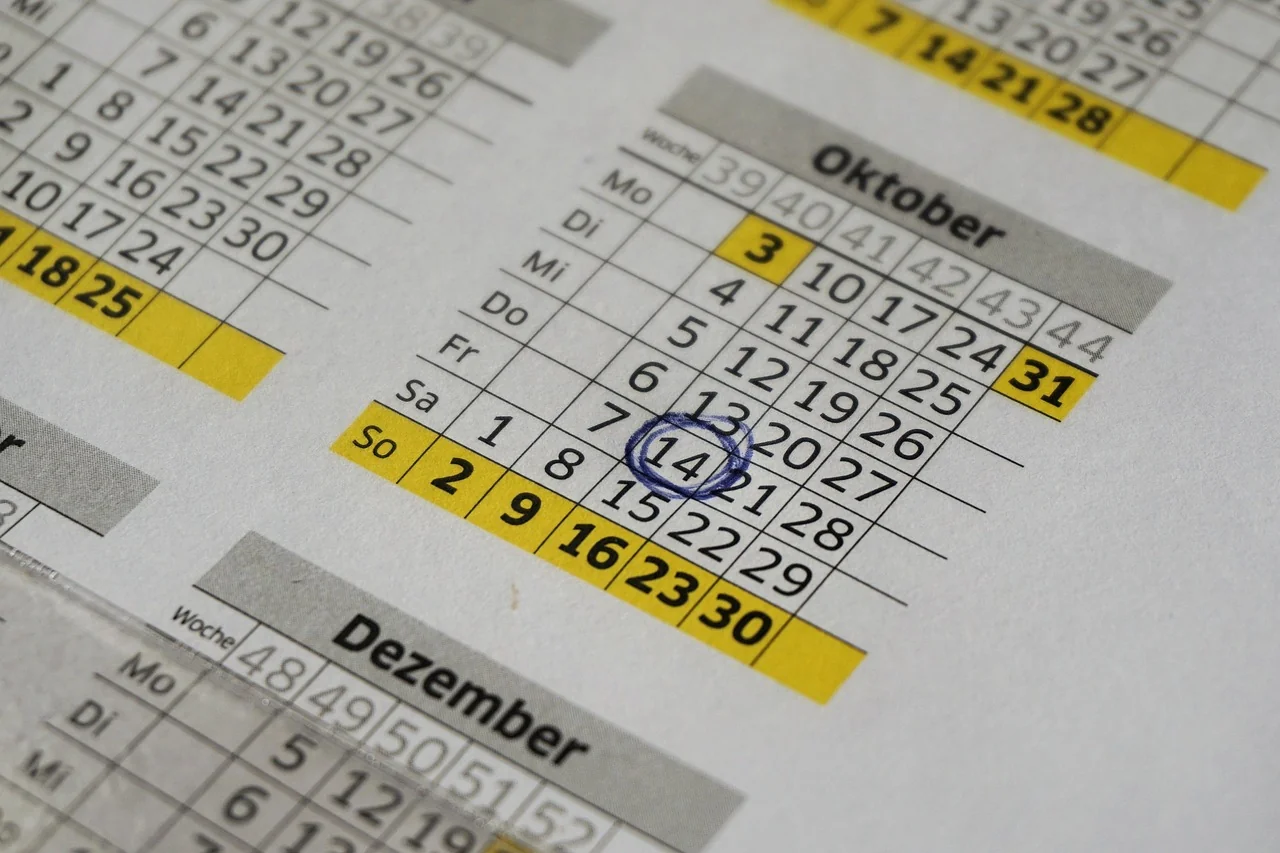 Kalender tahunan cetak dengan tanggal 14 Oktober dilingkari pena biru, pengingat batas setor pajak