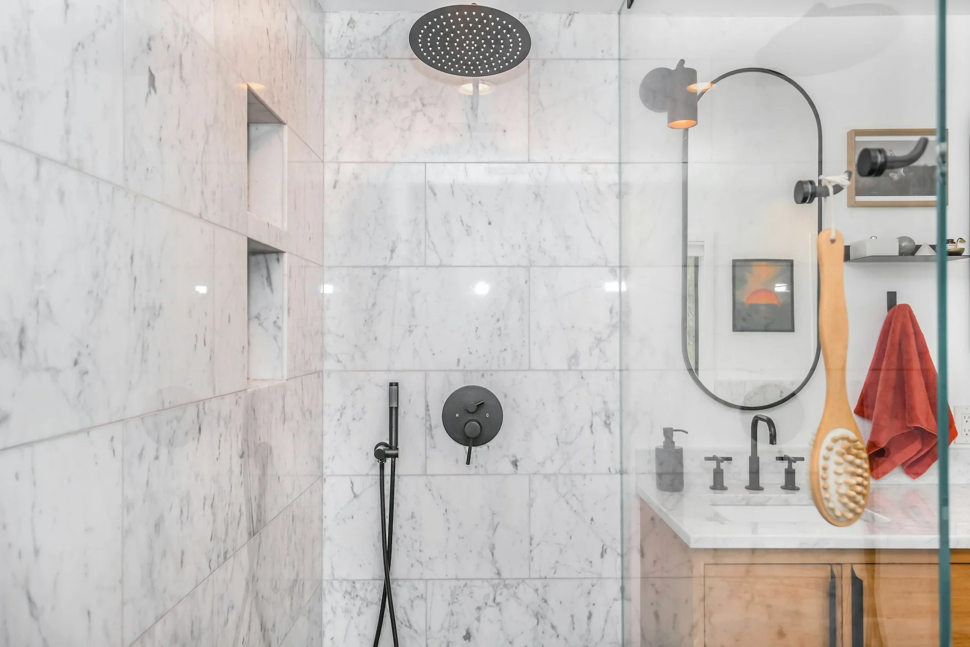 Kamar mandi berdinding marmer putih dengan rain shower hitam, keran pengatur, dan wastafel kayu