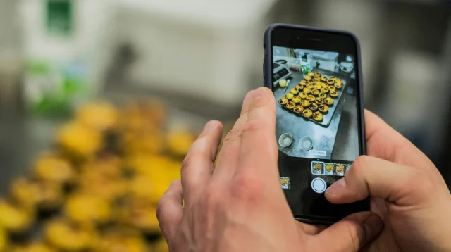 Tangan memotret deretan kue tart di atas loyang dengan kamera HP