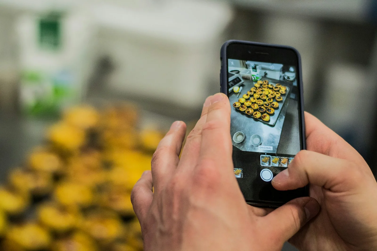 Tangan memotret deretan kue tart di atas loyang dengan kamera HP