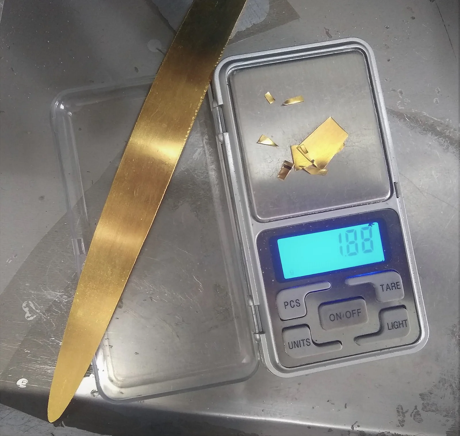 Potongan emas murni ditimbang di timbangan digital yang menunjukkan 1,88 gram