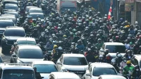 Ratusan pengendara sepeda motor memadati jalan kota di Indonesia, gambaran pilihan motor listrik vs motor bensin