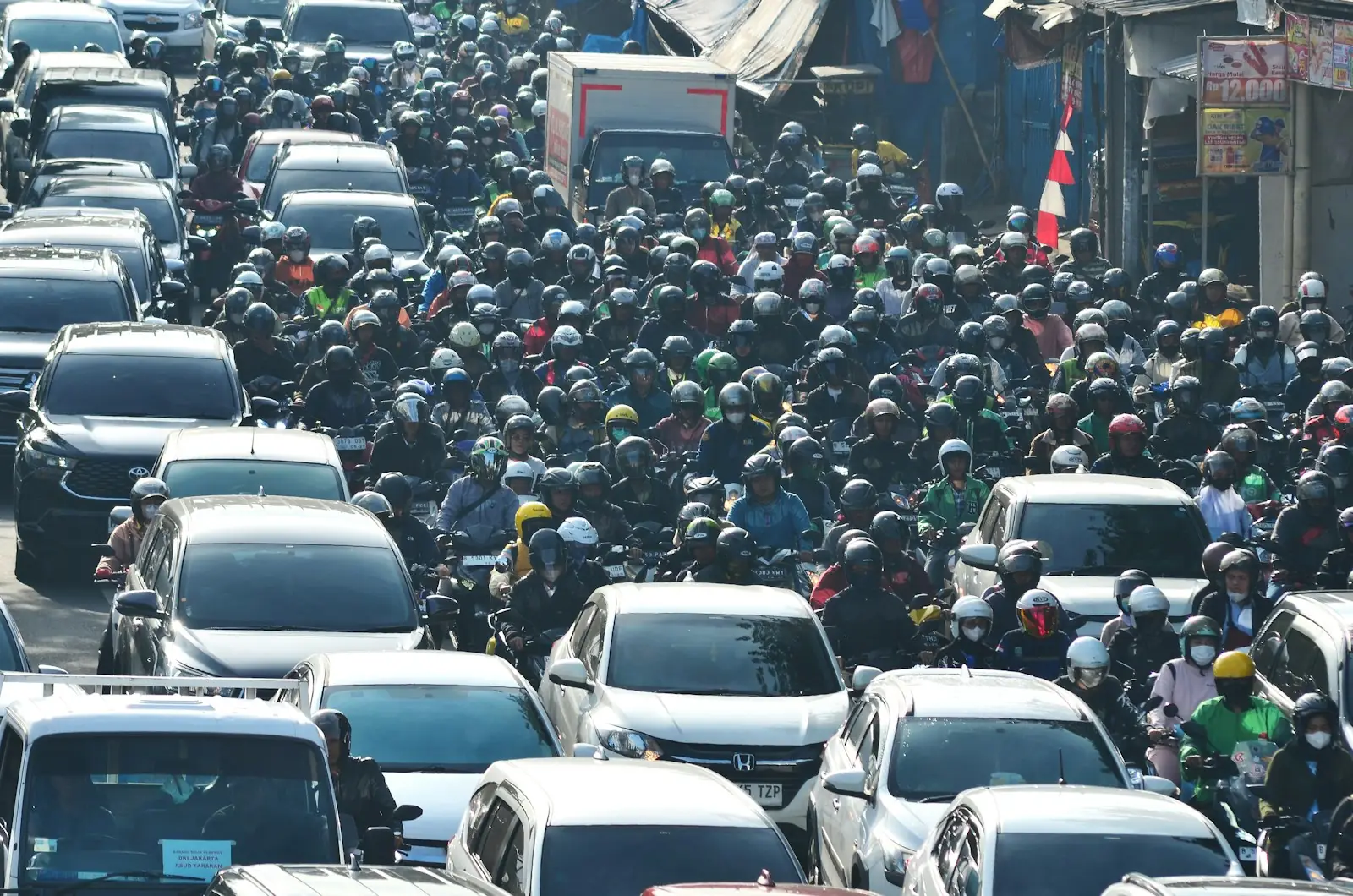 Ratusan pengendara sepeda motor memadati jalan kota di Indonesia, gambaran pilihan motor listrik vs motor bensin