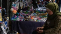 Pedagang pasar Garut memeriksa ponsel Pedagang perempuan di lapak pasar Garut memeriksa ponsel, ilustrasi cara hitung dan bayar PPh final UMKM