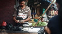 Pedagang pasar menghitung uang hasil jualan Pedagang di pasar tradisional menghitung uang hasil jualan, gambaran pencatatan omzet harian UMKM