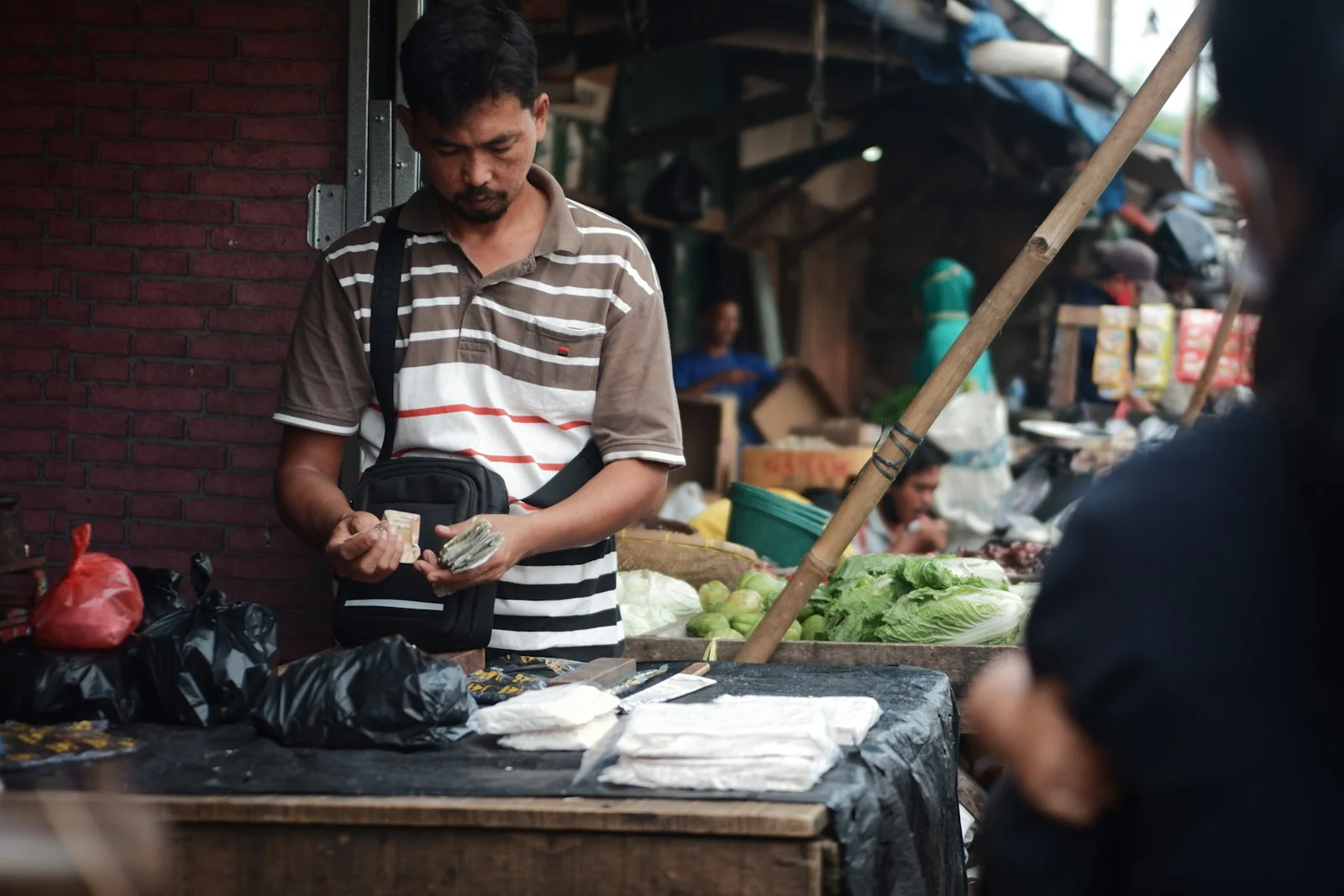 Pedagang di pasar tradisional menghitung uang hasil jualan, gambaran pencatatan omzet harian UMKM