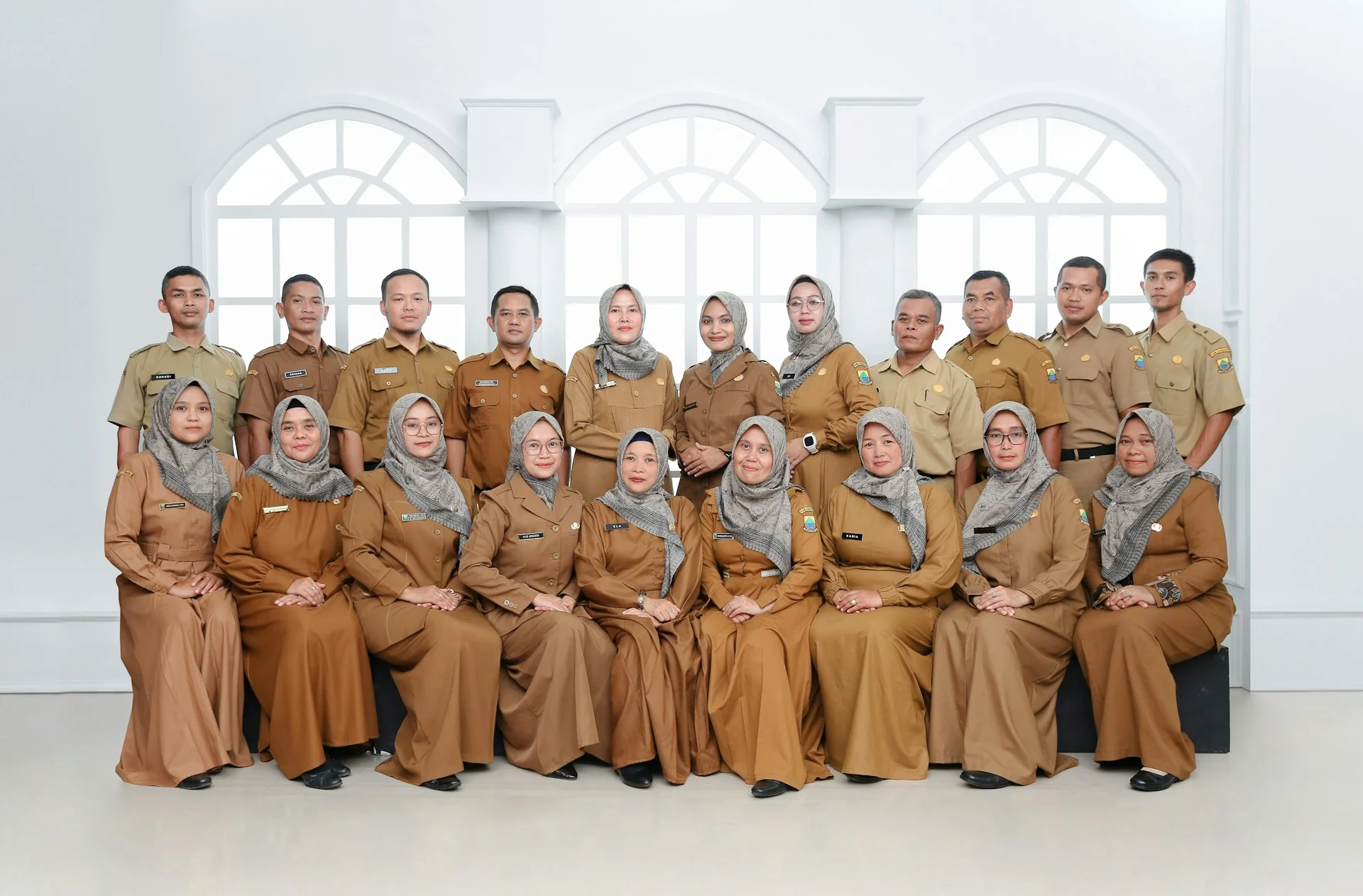 Sekelompok pegawai berseragam dinas cokelat khaki berfoto bersama di ruangan berjendela lengkung