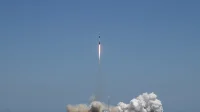Roket Falcon 9 meluncur membawa satelit Starlink dari Cape Canaveral, Florida, dengan kepulan asap di landasan