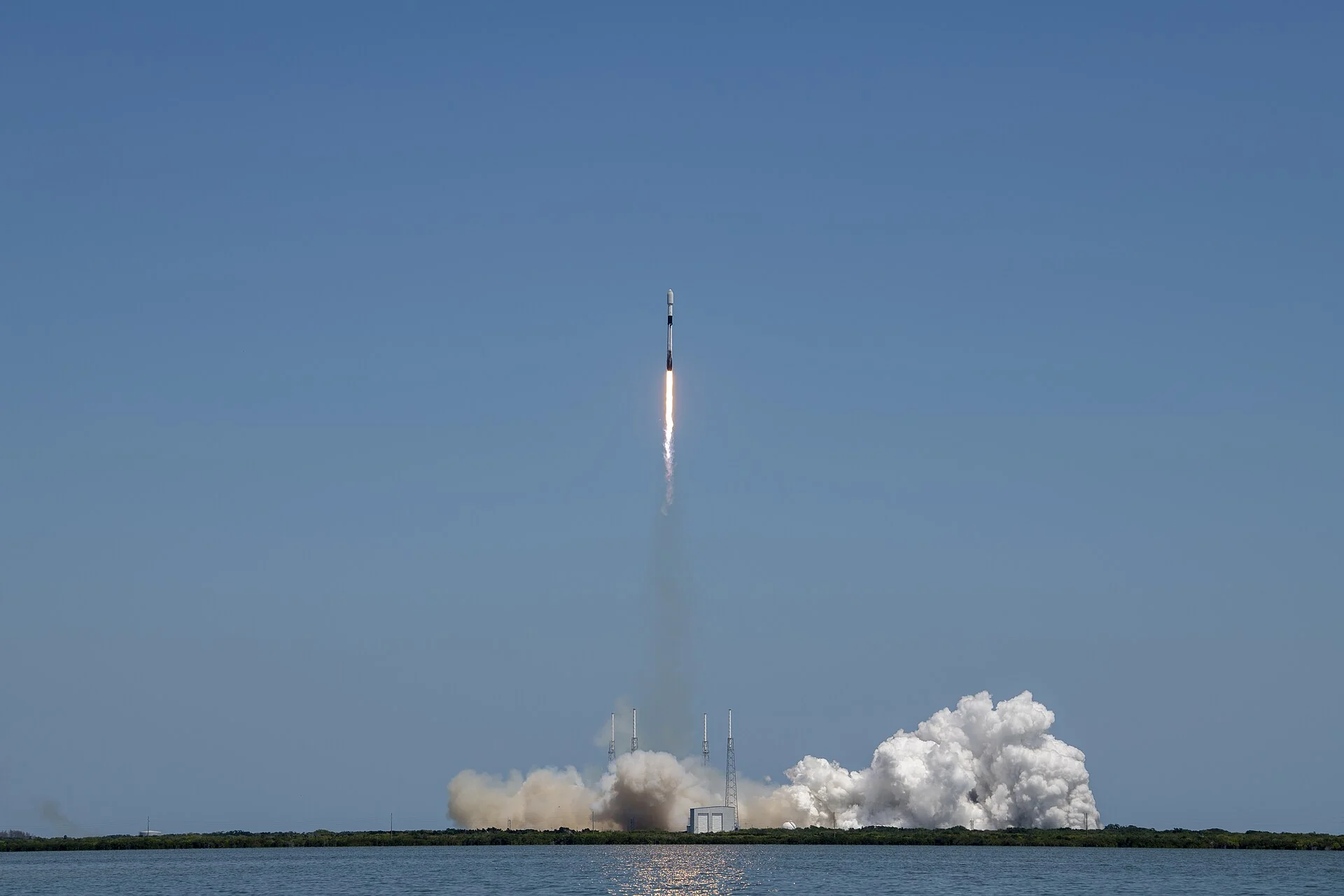Roket Falcon 9 meluncur membawa satelit Starlink dari Cape Canaveral, Florida, dengan kepulan asap di landasan