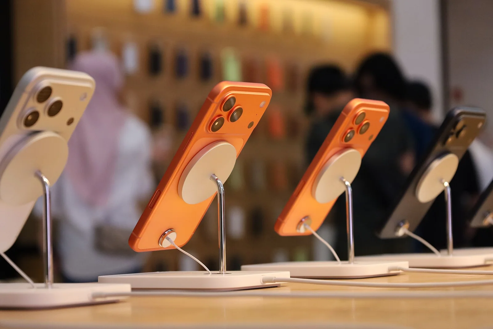 Deretan iPhone 17 Pro oranye dan putih di meja pajang saat peluncuran, pendahulu iPhone 18 biasa