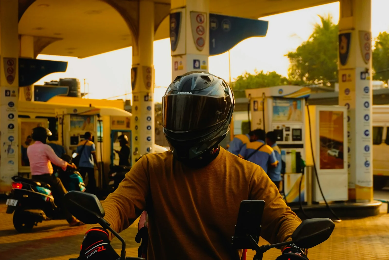 Pengendara motor berhelm menunggu giliran isi bensin di SPBU saat senja, contoh hitung harga BBM Oktober 2026