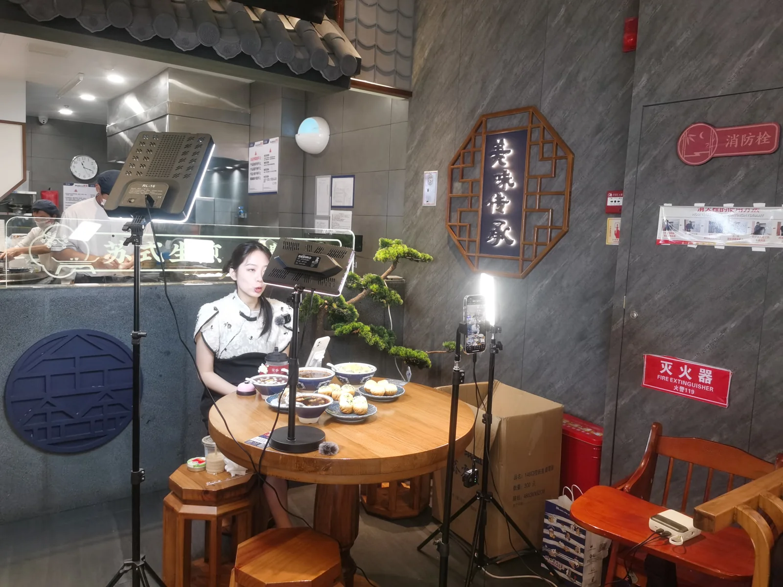 Cara jualan live: penjual siaran langsung memperkenalkan produk makanan di depan HP bertripod dan lampu LED